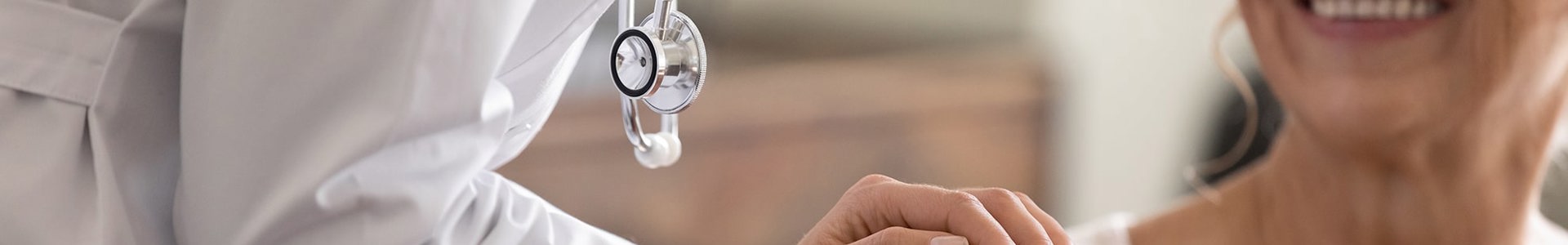Doctor warmly holding an international patient's hand during care.