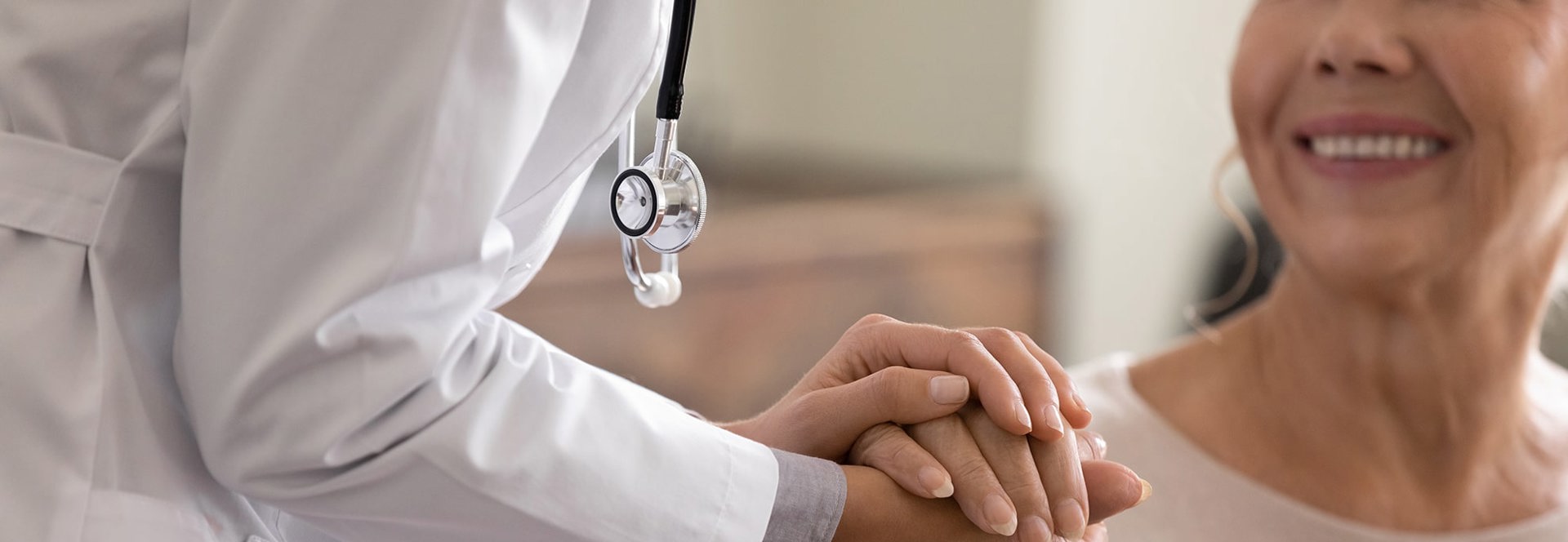 Doctor warmly holding an international patient's hand during care.