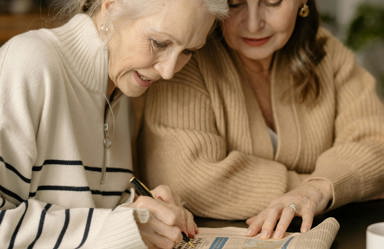 Two elderly women doing crossword puzzle for brain and memory health
